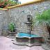 Hostal Los Volcanes, Guatemala City: stone courtyard with fountain, patio table, umbrella and potted palms