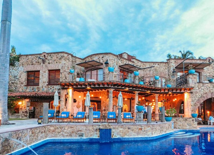 Casa Lisa in Acapulco with a stone terrace and blue-lit pool at dusk