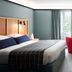 Haworth Hotel at Hope College in Holland guest room with king bed, desk, red chairs, and window view