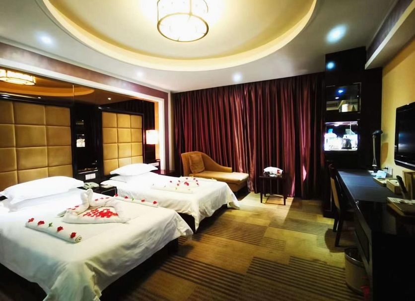 Huangtai International Hotel Jinan room with two beds, chaise lounge, desk and curtains
