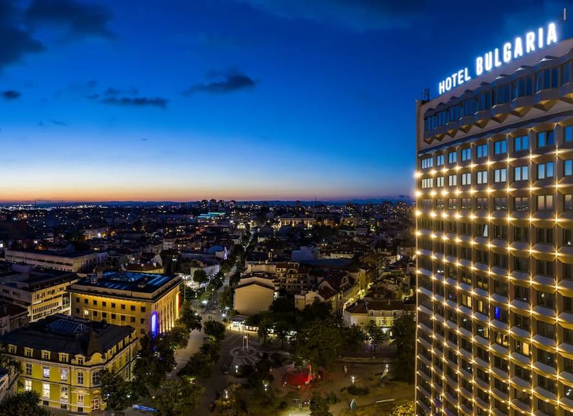 Hotel Bulgaria in Burgas with illuminated facade and city skyline at dusk