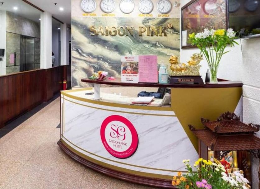 Saigon Pink Hotel reception desk in Ho Chi Minh City with floral decor and clocks on the wall