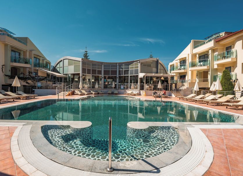 Belcehan Hotel in Fethiye with a large outdoor pool and sun loungers between resort buildings