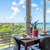 Castle @ Waikiki Grand Honolulu room with table and chairs, overlooking ocean and lush greenery