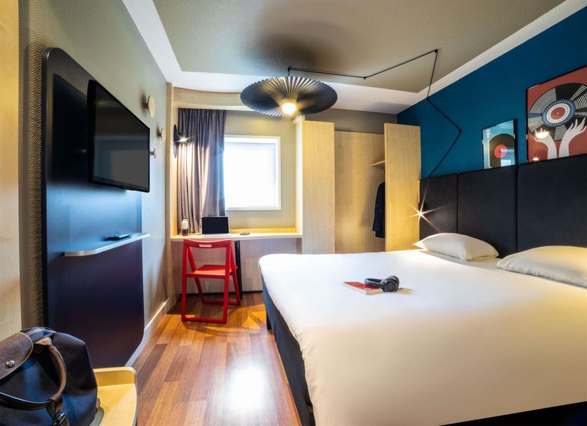 ibis Aulnay Paris Nord Expo room with double bed, desk by window, wall TV and colorful accent wall