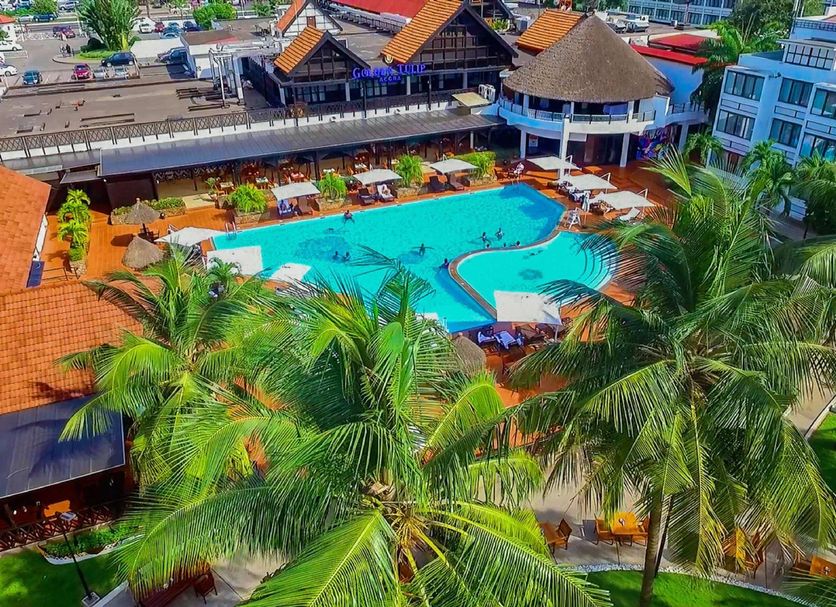 Lancaster Accra in Accra, aerial view of a resort pool surrounded by palm trees and lounge chairs
