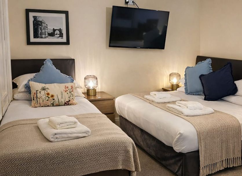 Dolgun Uchaf Guesthouse in Dolgellau twin room with two beds, bedside lamps, and wall-mounted TV