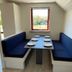 Grindsted Aktiv Camping dining nook with blue benches and set table by a window in Grindsted