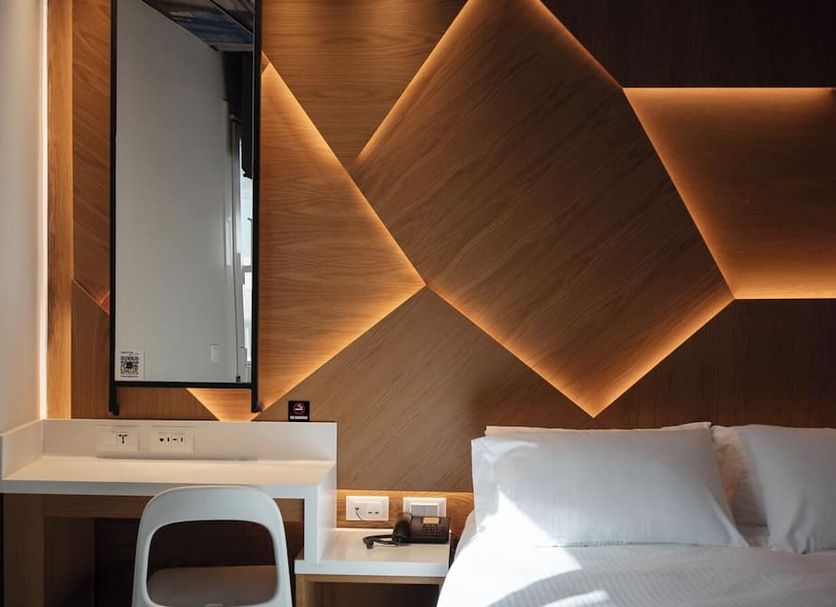 Kastro Hotel Heraklion room with illuminated geometric wood wall, desk and white bed