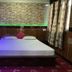 Sudha's Garden Home Kathmandu bedroom with king bed, stone accent wall, and patterned curtains