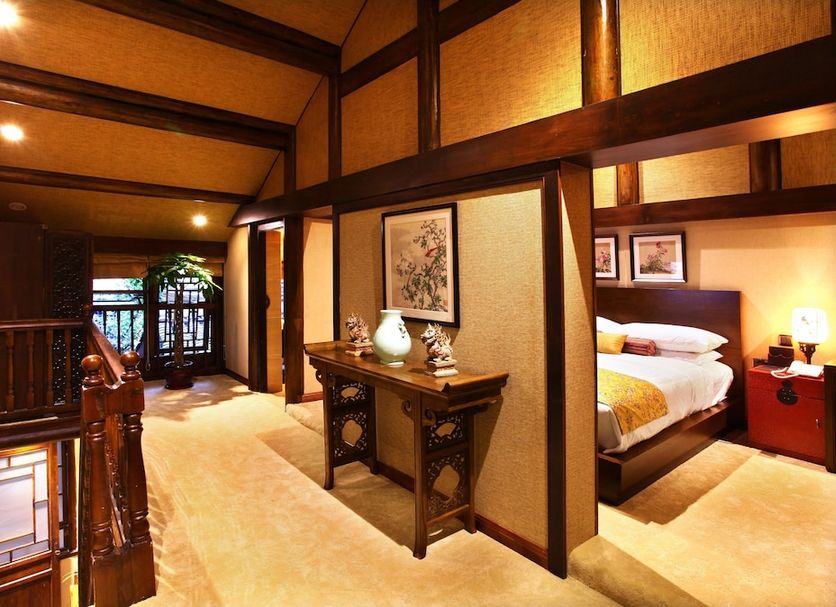Demen Renli Hotel in Chengdu: wood-paneled hallway leading to a cozy bedroom suite