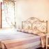 Alla Torre Del Barbarossa B&b Foresteria room with wrought-iron bed, window and patterned curtains in Mandello del Lario