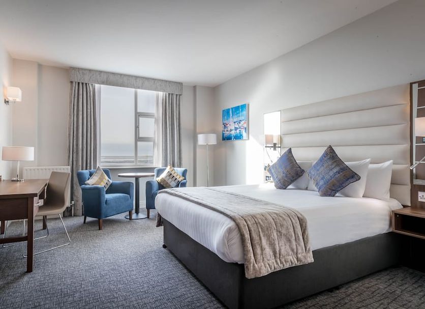 Marine Hotel Dublin guest room with king bed, seating area and city view through large window