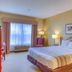 Country Inn & Suites by Radisson, Crystal Lake, IL guest room with king bed, chair, and window seating