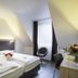 Achat Hotel Monschau room with two single beds, desk, chair, and window with curtains in Monschau