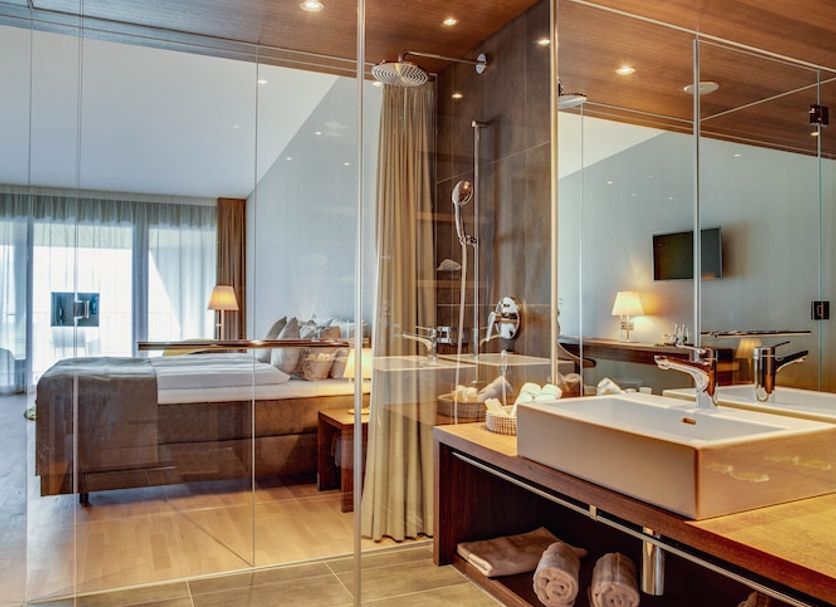 Gasthaus Badhof in Lucerne bathroom with glass shower, double sink vanity and bedroom beyond