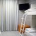 Hi Rabin - Jerusalem Hostel dorm room with bunk beds, curtained window, TV and orange ottoman in Jerusalem