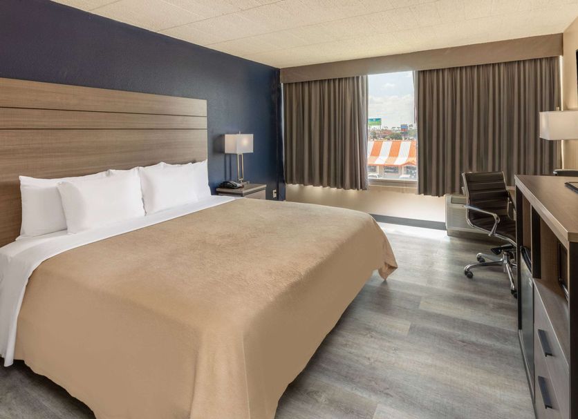 Baymont by Wyndham Laredo guest room with king bed, desk, and city view through large window