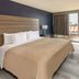 Baymont by Wyndham Laredo guest room with king bed, desk, and city view through large window
