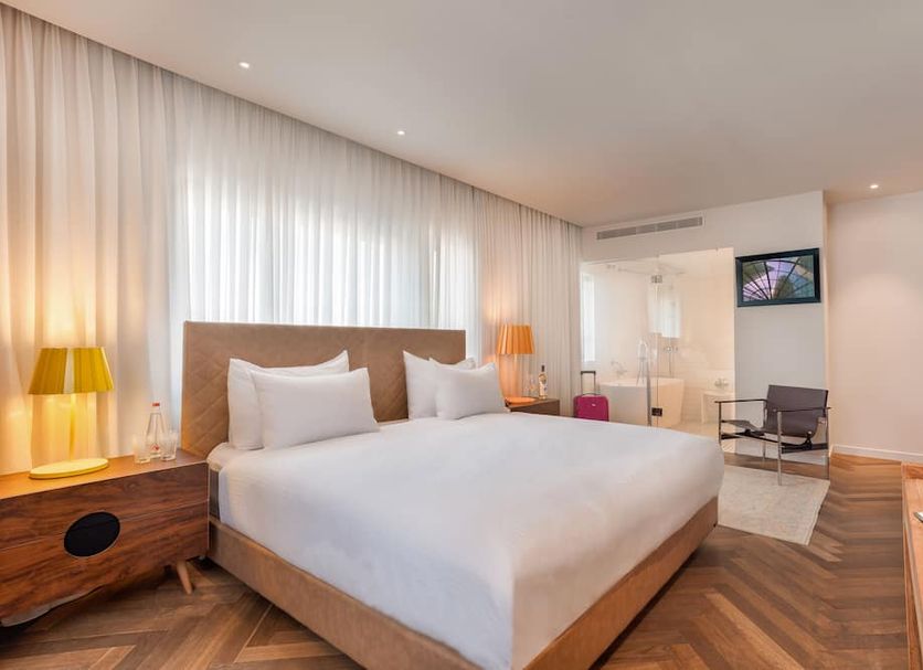 Shenkin Hotel Tel Aviv room with king bed, wood flooring, bedside lamps, and seating area
