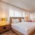 Shenkin Hotel Tel Aviv room with king bed, wood flooring, bedside lamps, and seating area