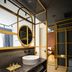 Colors Hotel Athens bathroom with round vessel sink, black marble vanity and gold-framed shelving in Athens