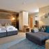 Familienparadies Sporthotel Achensee room with twin beds, sofa, armchair and modern seating area in Achenkirch