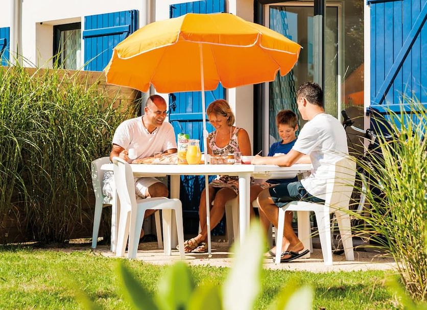 Lagrange Vacances Domaine de Val Queven in Gestel, family dining outdoors under an orange umbrella