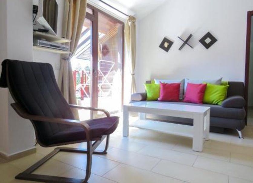 Flora Daisy Apartment in Borovets with black lounge chair, sofa, and balcony door
