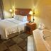 Hampton Inn Garden City guest room with king bed, bedside lamps, and bathtub