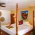 The Colonial at Jaguar Reef in Hopkins: four-poster bed, colorful art, woven wall decor, and floor lamp