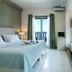 Kenta Beach Hotel in Agios Ioannis guest room with balcony sea view, bed and patterned sofa