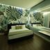 Le Palazzine Hotel in Vlorë guest room with tropical leaf wall mural, bed, TV and illuminated vanity