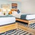 Surf House in Hampton guest room with two wooden beds, blue accents, and framed beach art