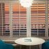 Casa Loma in Panama City Beach: ocean-view room with white table, teal chairs, and sunset beyond shutters