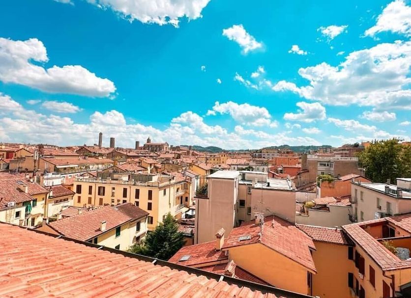 Ostello Bello Bologna rooftop view over Bologna’s terracotta rooftops under a bright blue sky.
