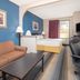 Baymont by Wyndham Laurel guest room with bed, sofa, desk chair and TV