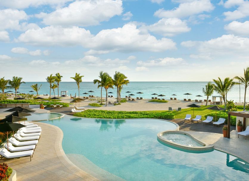 Rosewood Mayakoba in Playa del Carmen with a beachfront infinity pool, loungers, palm trees and ocean view