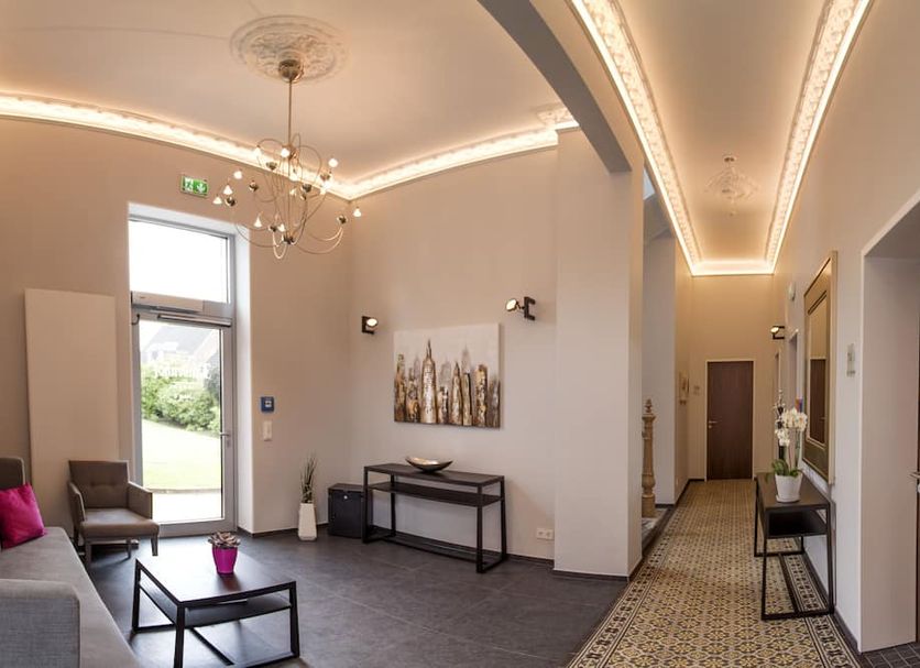 Hotel Lindenhof Emsdetten lobby with chandelier, seating, console table and long hallway