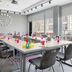 Moxy Asheville Downtown meeting room with long conference table, colorful chairs, and floor-to-ceiling windows in Asheville