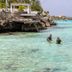 Grand Windsock Bonaire in Kralendijk with clear turquoise water and people snorkeling by the shore