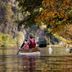 Hotel Deutschherrenhof in Zeltingen-Rachtig with guests kayaking on a calm river beside vineyard slopes.