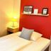 Hotel Friedrichstraße, Lampertheim guest room with twin beds, red accent wall, lamp and window