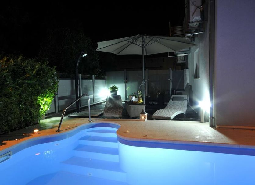 Apartments & Rooms Villa Maslina in Trogir with a lit outdoor pool and terrace lounge at night