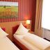 Stadthotel Augsburg guest room with two single beds, red striped walls, and a landscape painting in Augsburg