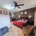 Royal Game Guest House in Phalaborwa bedroom with brick accent wall, red bedspread and wicker chair