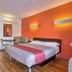 Motel 6 Santa Rosa - South guest room with bed, orange accent wall, and sitting area in Santa Rosa