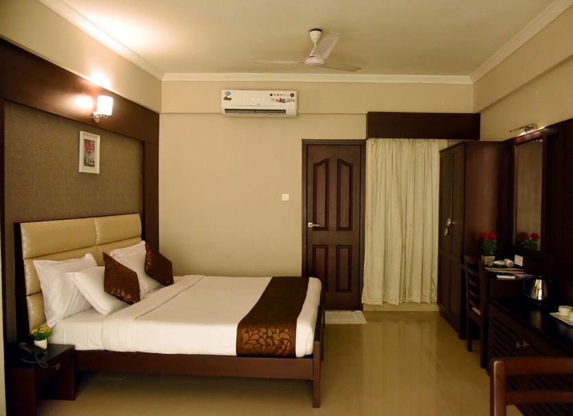 Hotel Pearl International in Chennai guest room with double bed, wardrobe, desk, and air conditioning