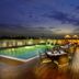 Mahagun Sarovar Portico Suites Ghaziabad rooftop pool deck with dining tables at dusk