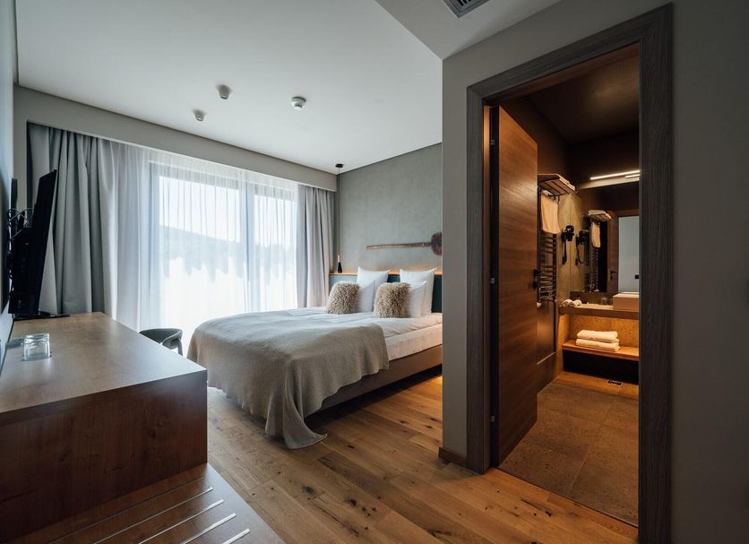 Balvanyos Resort in Baile Balvanyos: modern guest room with bed, wood floors, and bathroom entry